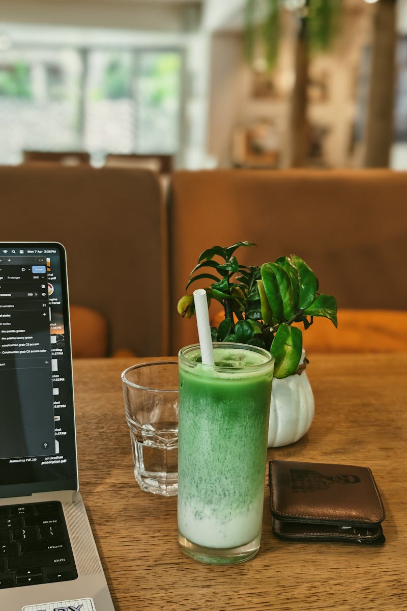 A cozy cafe setup featuring a laptop, matcha latte, and greenery, ideal for freelancers.